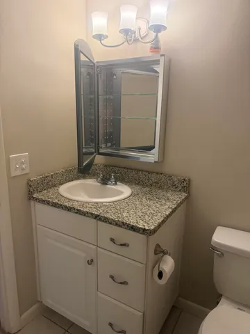 a bathroom with a granite countertop sink a toilet and a mirror