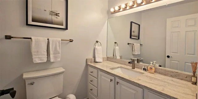 a bathroom with a granite countertop sink mirror and toilet