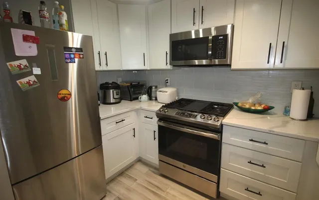 a kitchen with stainless steel appliances granite countertop a refrigerator and a stove top oven