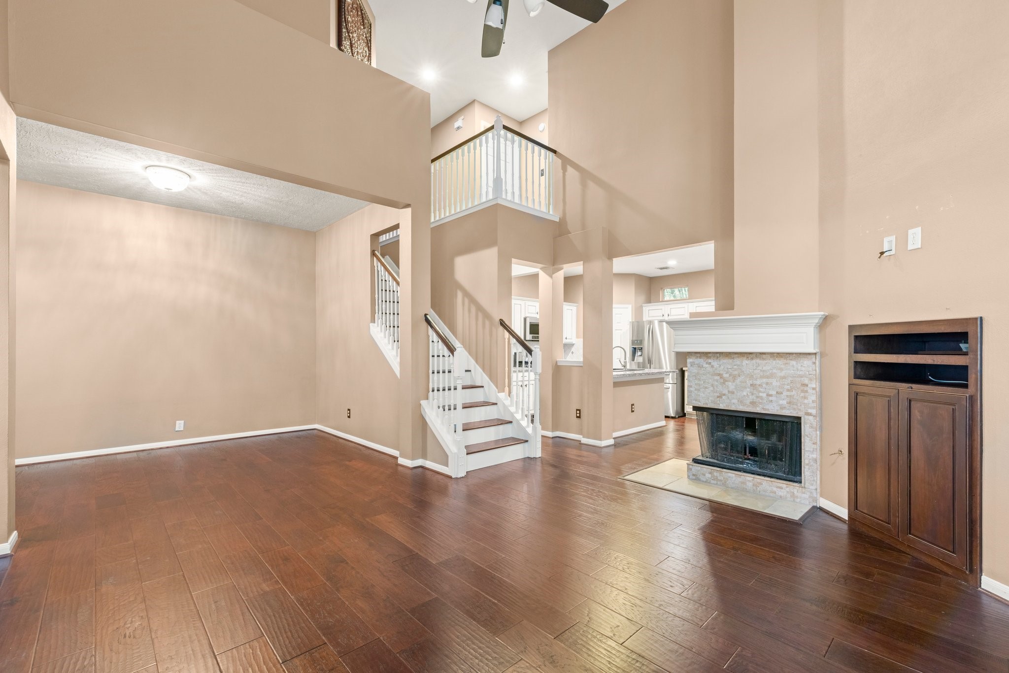 a view of an empty room with wooden floor fireplace and a window