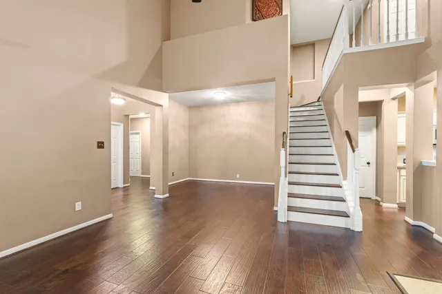 a view of an empty room with wooden floor and stairs