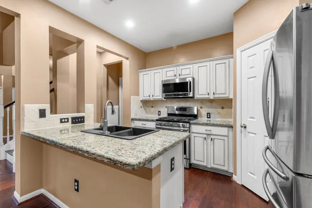 a kitchen with stainless steel appliances granite countertop a stove a sink and a refrigerator
