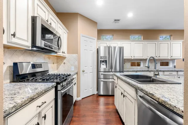 a kitchen with stainless steel appliances granite countertop a sink stove and refrigerator