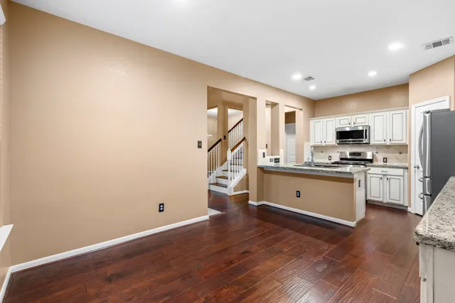 a kitchen with a refrigerator stove and wooden floor