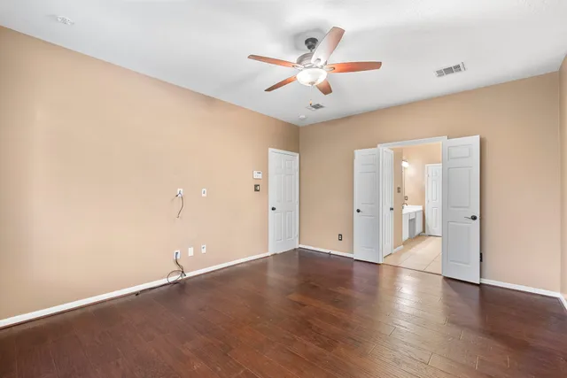 an empty room with wooden floor and windows