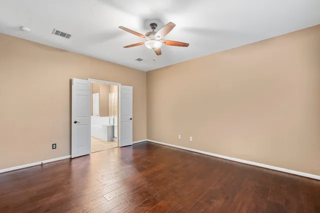 an empty room with wooden floor and a ceiling fan