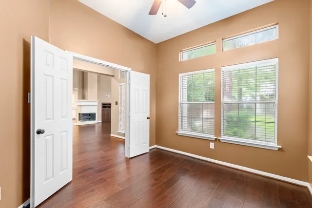a view of empty room with wooden floor and fan