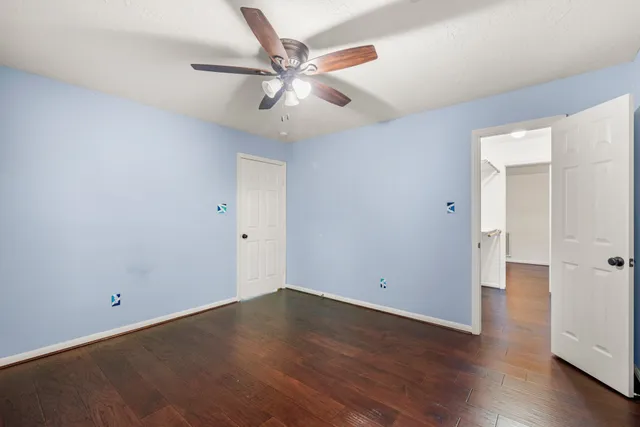 an empty room with wooden floor and ceiling fan