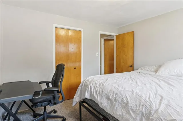 a bedroom with a bed a desk and chair with rug