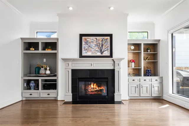 a view of an empty room with wooden floor fireplace and a window