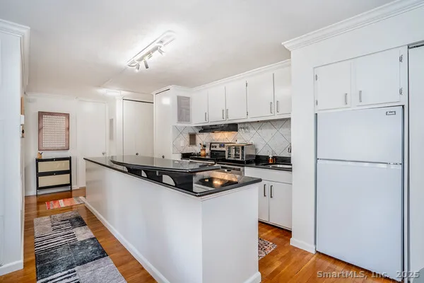 a kitchen with stainless steel appliances a refrigerator a stove and white cabinets