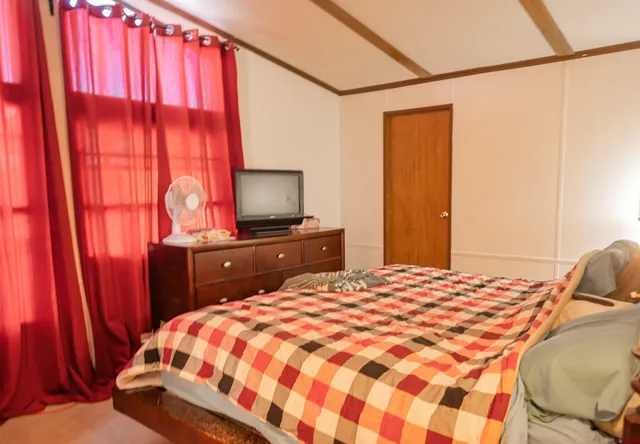 a bedroom with a bed and a flat tv screen on dresser
