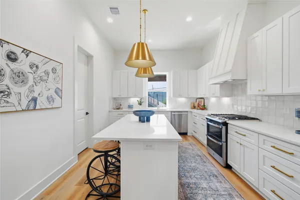 a kitchen with stainless steel appliances granite countertop a sink a stove a refrigerator and cabinets