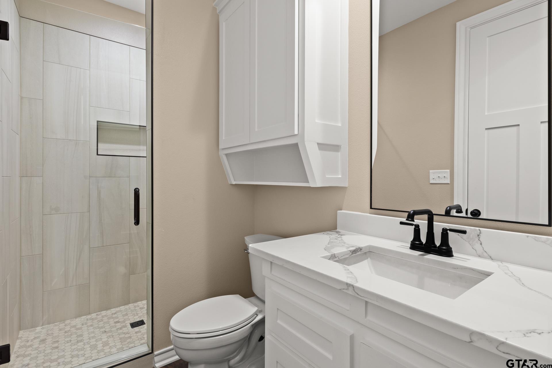 1003 Stone Haven Mount Pleasant, TX 75455 - Photo 28 of 41 a bathroom with a sink toilet a mirror and shower