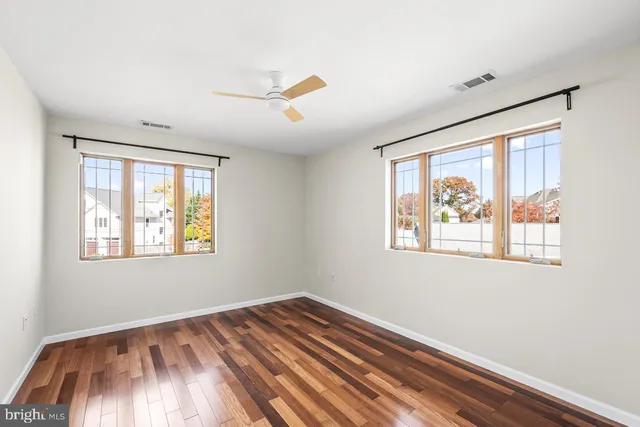 a view of empty room with wooden floor and fan