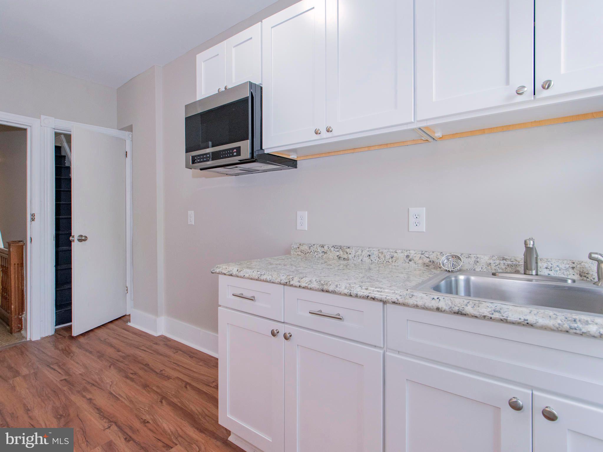 14 West 3rd Street, Unit 2 Pottstown, PA 19464 - Photo 5 of 13 a kitchen with granite countertop white cabinets and a wooden floor