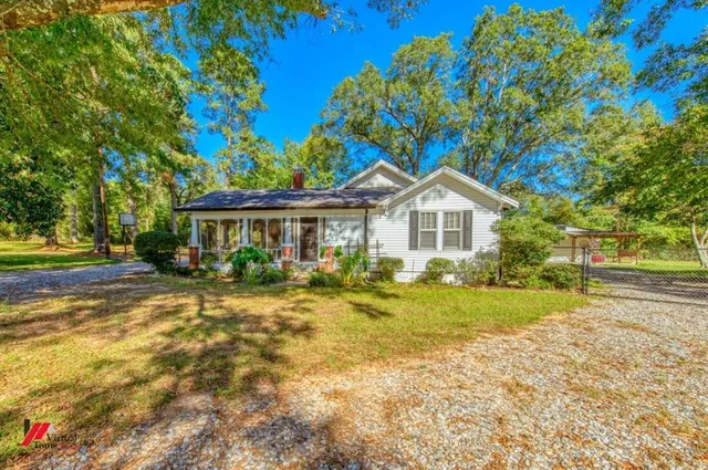 a front view of a house with a garden and trees