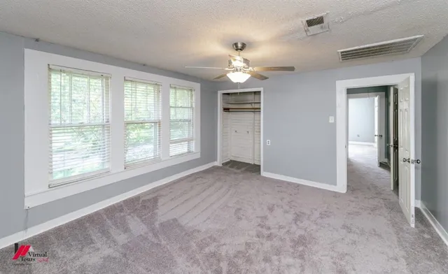 an empty room with windows and chandelier fan