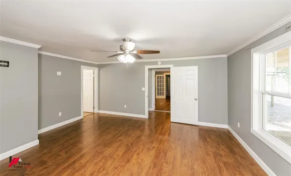 a view of an empty room with wooden floor and a window