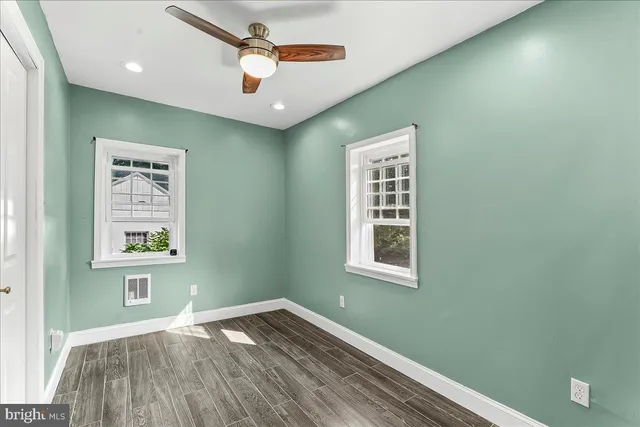 a view of an empty room with window and wooden floor