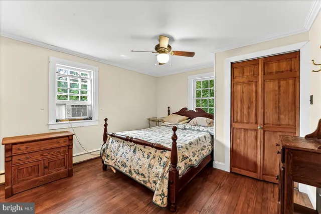 a bedroom with a bed a dresser with wooden floor