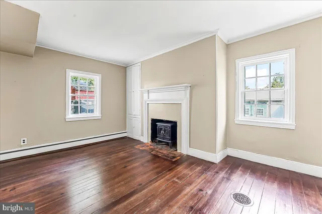 an empty room with windows a fireplace and wooden floor