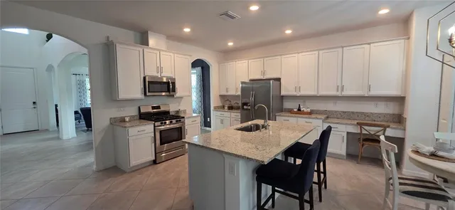 a kitchen with a refrigerator a stove a sink a dining table and chairs