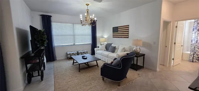 a living room with furniture a chandelier and a flat screen tv