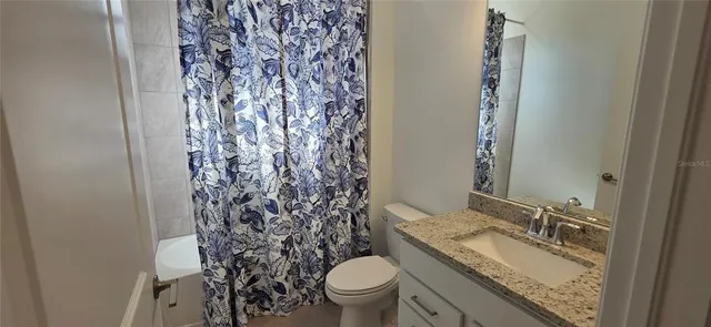 a bathroom with a granite countertop sink toilet and a mirror