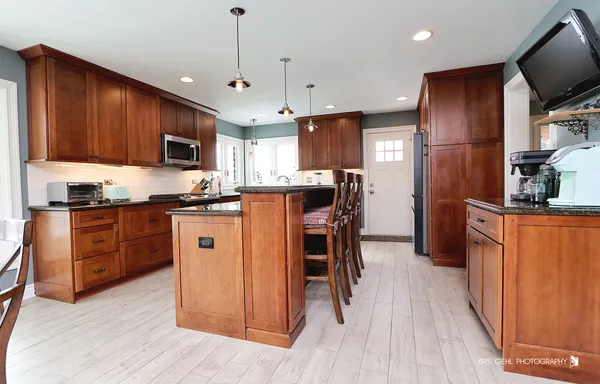 a kitchen with stainless steel appliances granite countertop a refrigerator a stove top oven a sink dishwasher and wooden cabinets with wooden floor
