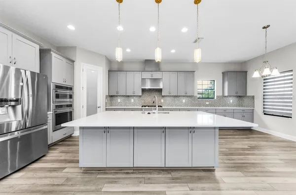 a kitchen with stainless steel appliances granite countertop a sink a refrigerator and a view of living room