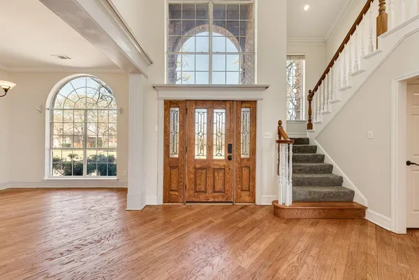 an empty room with wooden floor fan and a window