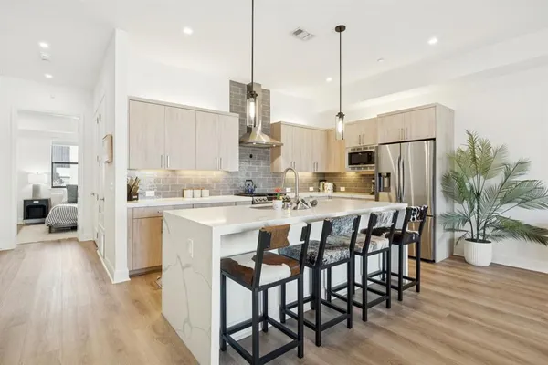 a kitchen with kitchen island stainless steel appliances a dining table chairs sink and cabinets