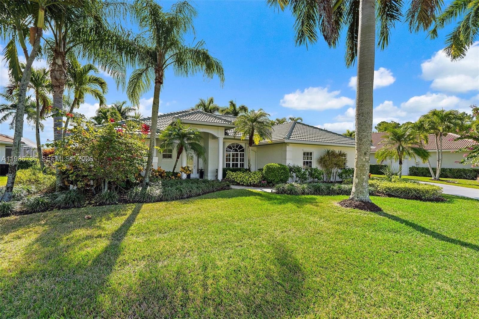 8185 Southeast Double Tree Drive Hobe Sound, FL 33455 - Photo 2 of 40 a front view of a house with a yard and palm trees