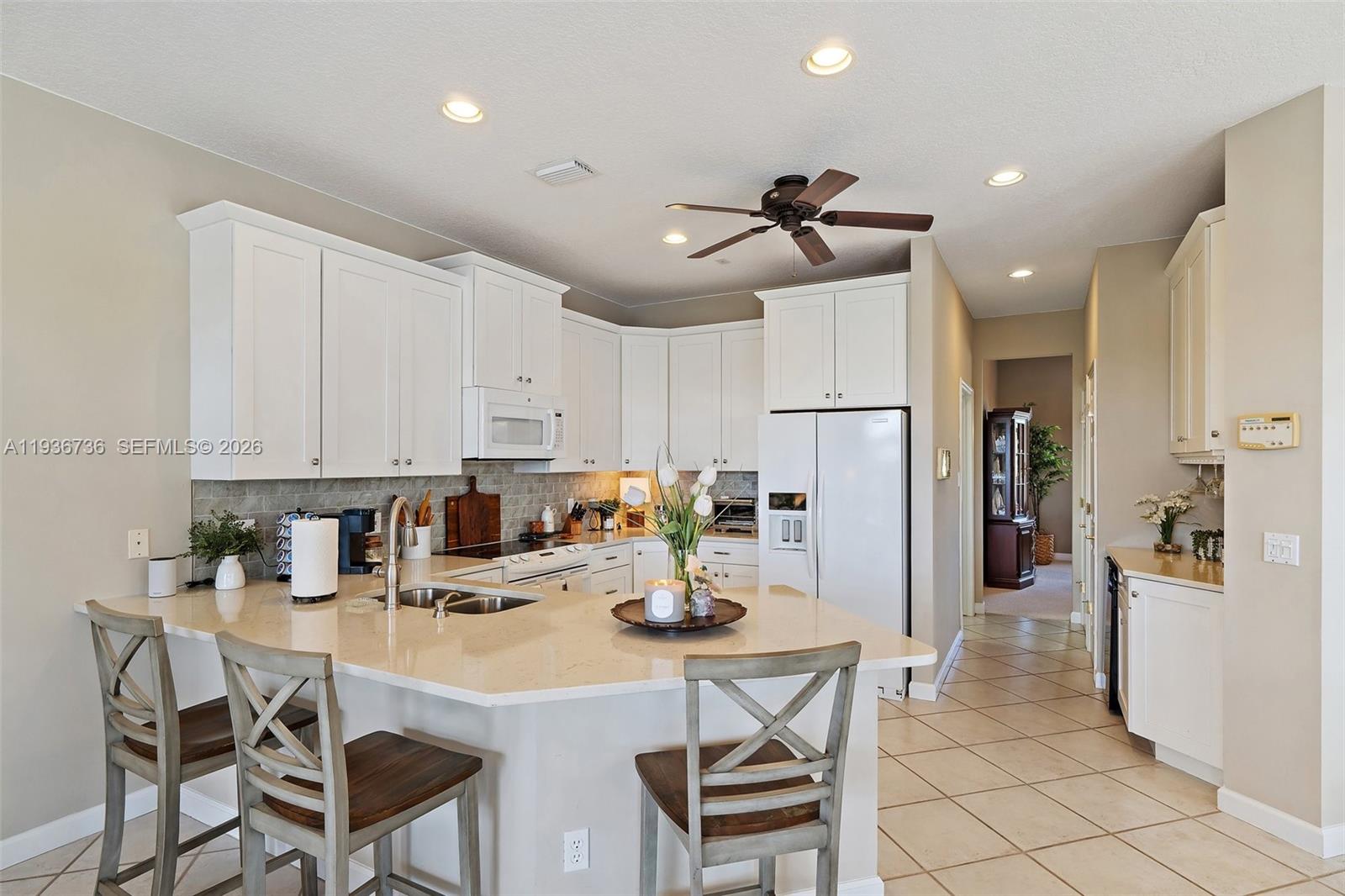 8185 Southeast Double Tree Drive Hobe Sound, FL 33455 - Photo 8 of 40 a kitchen with a refrigerator and chairs