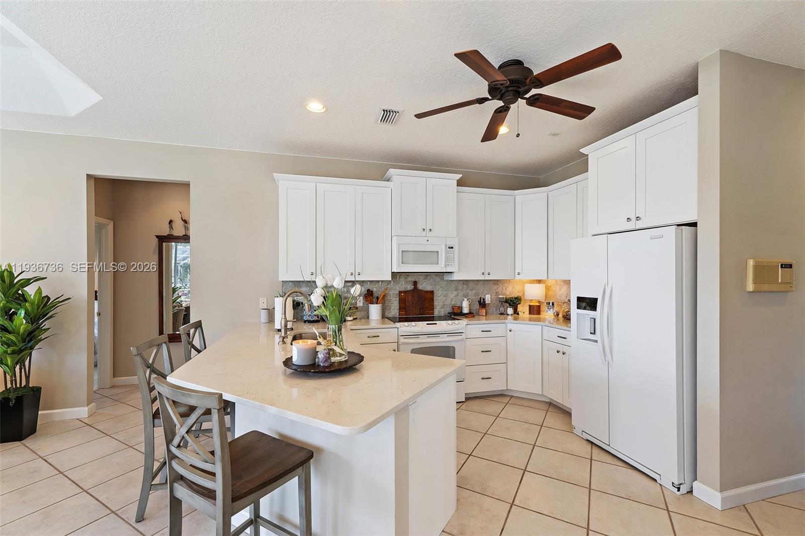 8185 Southeast Double Tree Drive Hobe Sound, FL 33455 - Photo 9 of 40 a kitchen with a refrigerator a white table and chairs