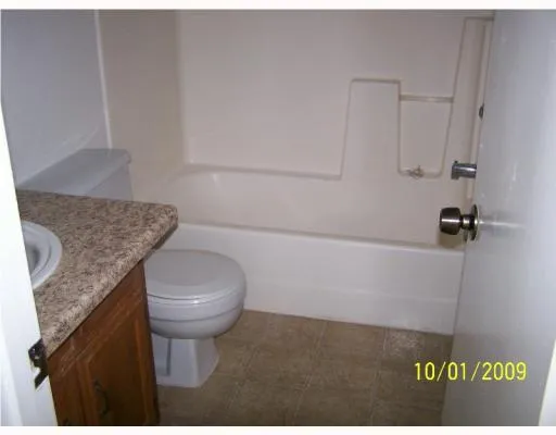 a bathroom with a granite countertop toilet sink and mirror