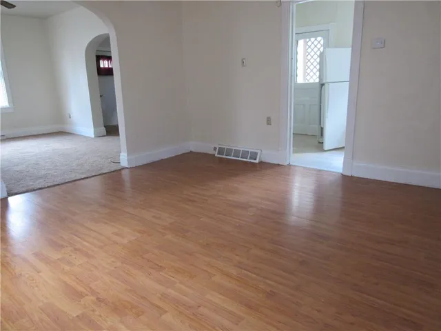 an empty room with wooden floor and mirror