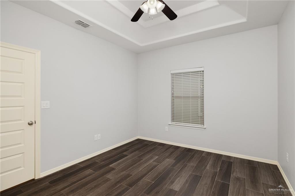 1801 Jackson Street Weslaco, TX 78599 - Photo 5 of 15 an empty room with wooden floor chandelier fan and windows