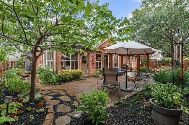 a backyard of a house with table and chairs under an umbrella