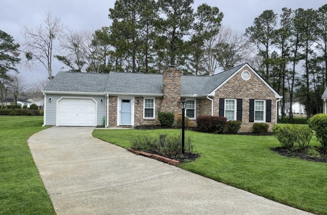Ranch-style house with driveway, a shingled roof, a front yard, brick siding, and a garage