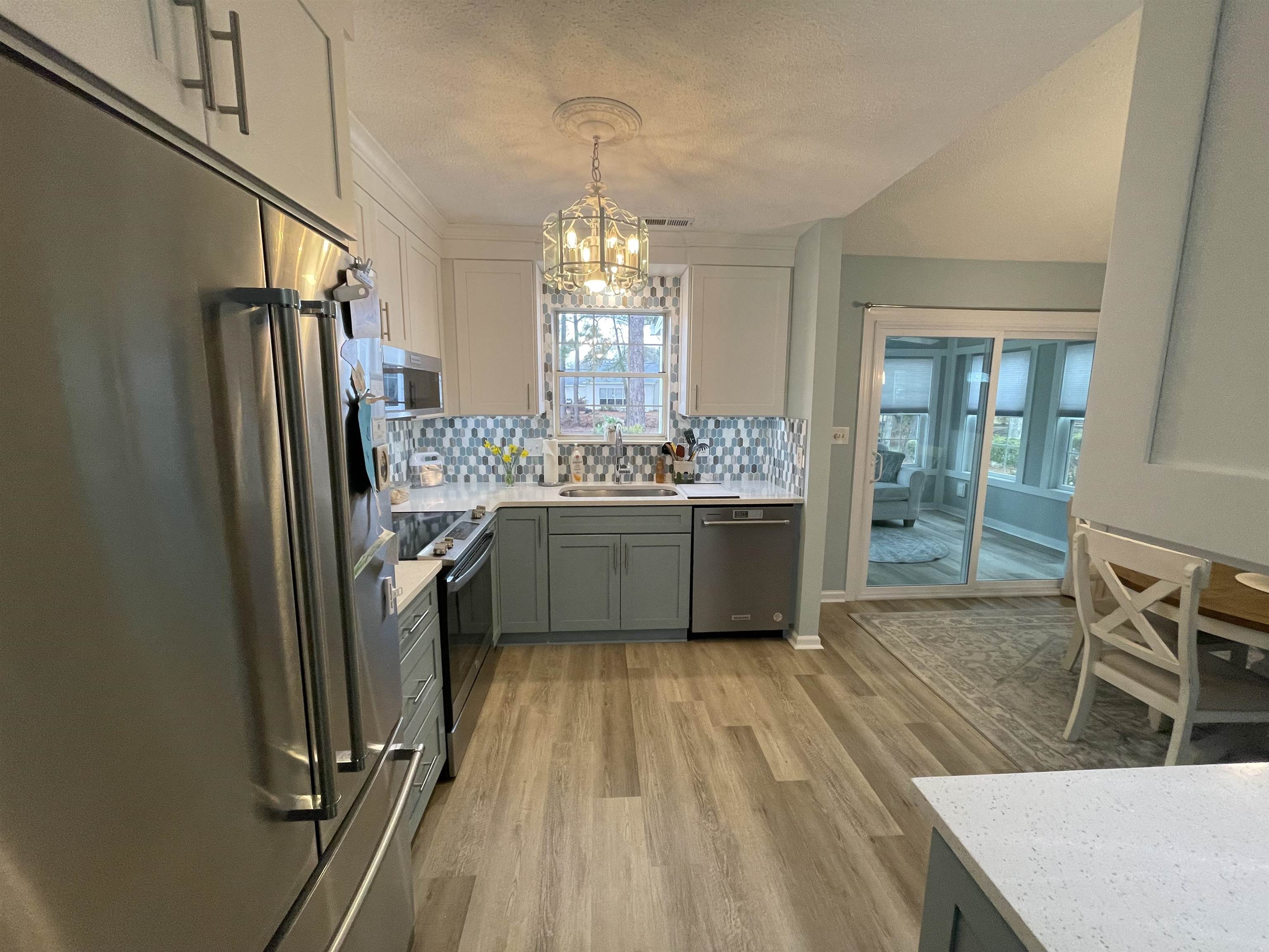 505 Night Heron Court Murrells Inlet, SC 29576 - Photo 7 of 27 Kitchen featuring gray cabinets, appliances with stainless steel finishes, white cabinets, light wood finished floors, and decorative backsplash