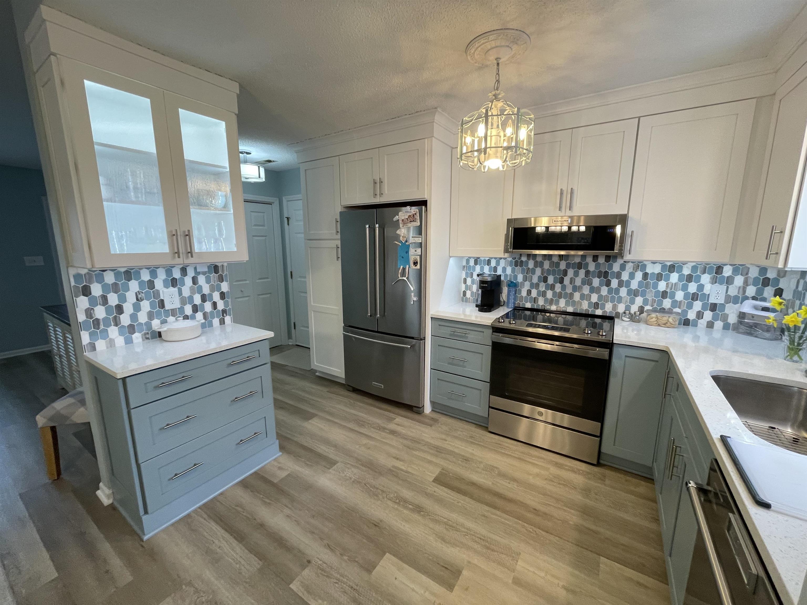 505 Night Heron Court Murrells Inlet, SC 29576 - Photo 9 of 27 Kitchen with gray cabinets, white cabinetry, stainless steel appliances, decorative backsplash, and light stone counters