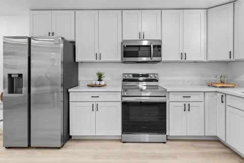 a kitchen with white cabinets and stainless steel appliances