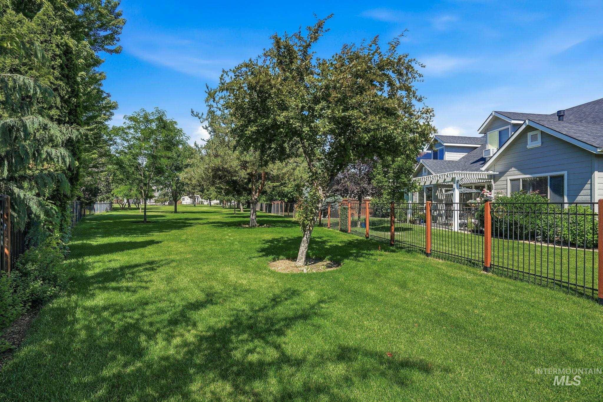3969 North Hollymount Way Meridian, ID 83646 - Photo 44 of 47 Expansive green lawn with established trees, bordering a black metal fence with wood posts