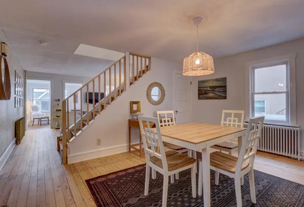 a dining room with wooden floor a chandelier a wooden table and chairs