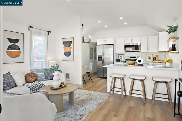 a living room with stainless steel appliances a dining table and chairs