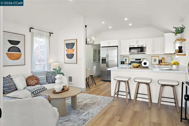 a living room with stainless steel appliances a dining table and chairs
