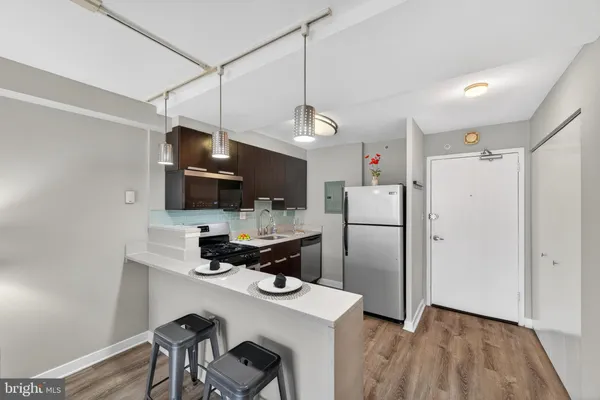a kitchen with stainless steel appliances a refrigerator a sink dishwasher a stove and white cabinets with wooden floor
