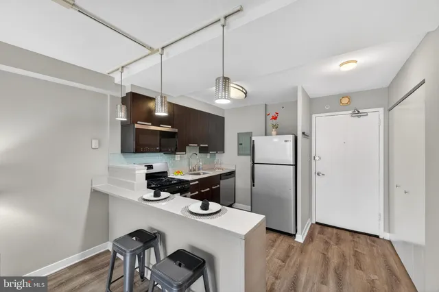 a kitchen with stainless steel appliances a refrigerator a sink dishwasher a stove and white cabinets with wooden floor